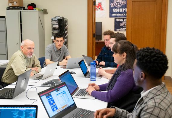 Image of students collaborating with a faculty member.